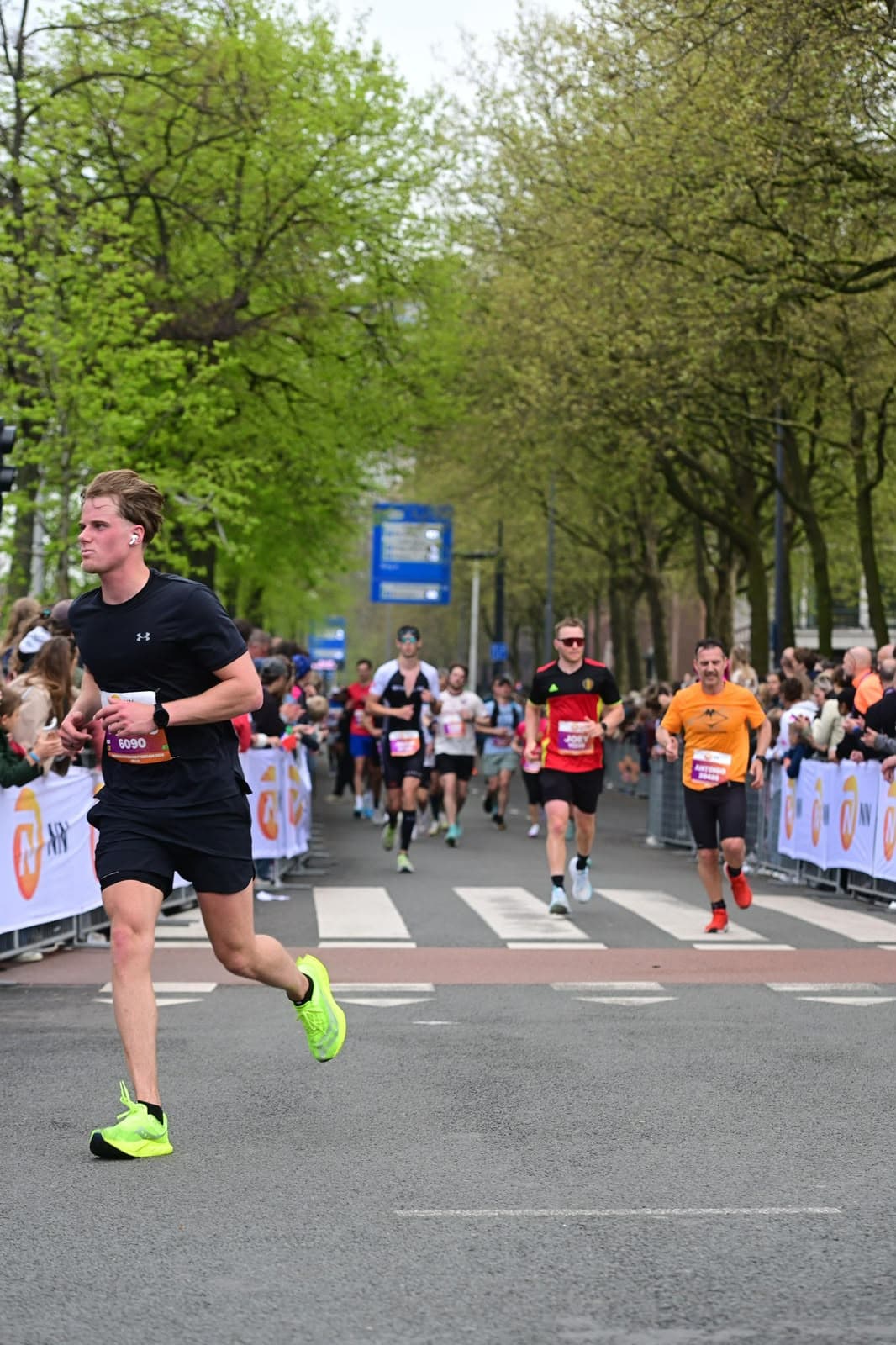 Teun loopt de marathon van Rotterdam, met andere lopers en publiek achter hem.